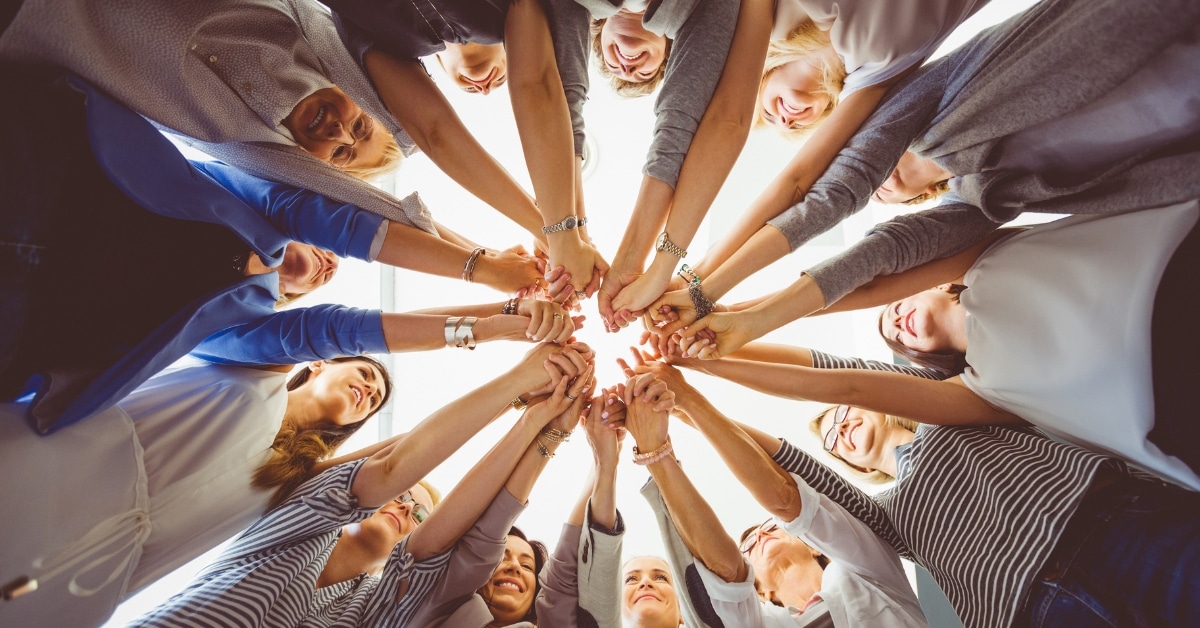 In Utah, a group of people standing in a circle reach their hands toward the center, joining them together in support and unity. This symbolizes the strength found through community in overcoming challenges like alcohol and drug abuse with effective treatment services.